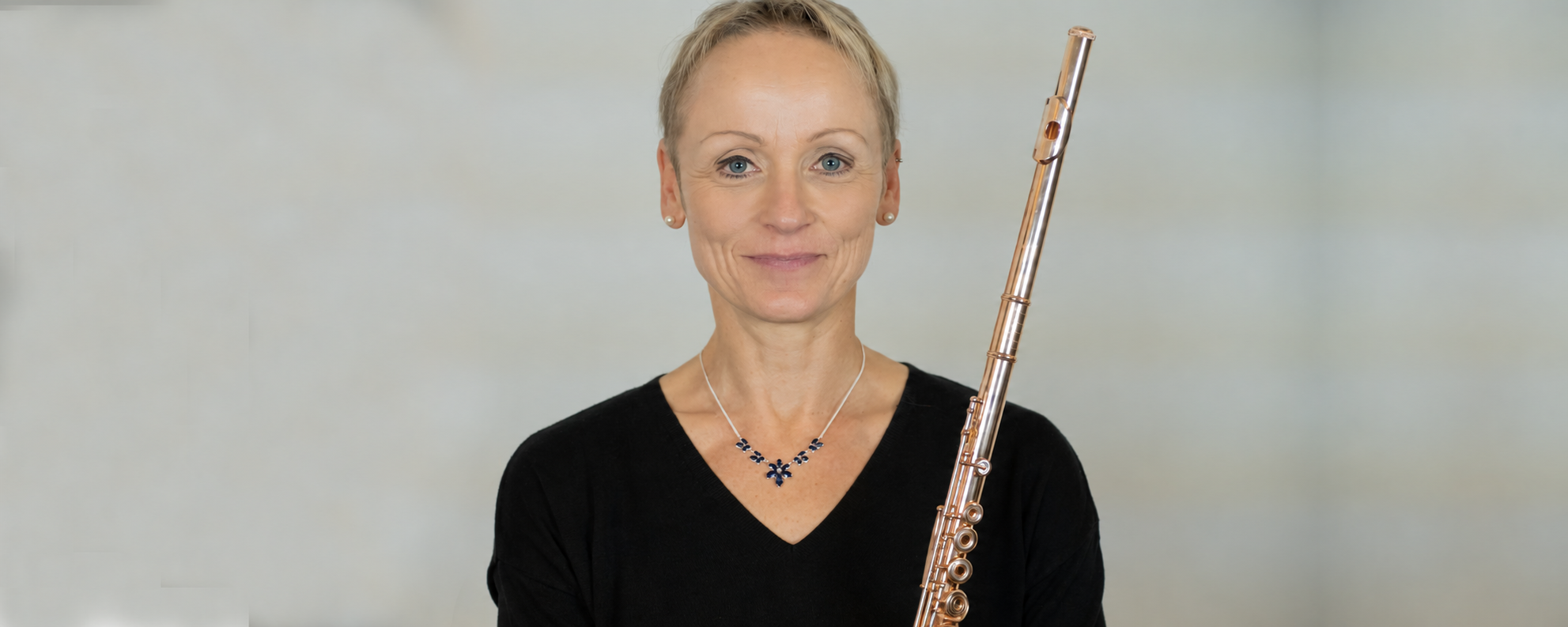 Katja Reinbold mit ihrer Querflöte vor hellem grauem Hintergrund